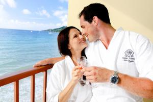 a man and woman drinking wine on a balcony with the ocean at Coral Strand Smart Choice in Beau Vallon