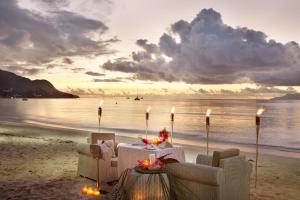 a table and chairs on the beach with a sunset at Coral Strand Smart Choice in Beau Vallon