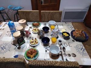 una mesa con comida para el desayuno y bebidas en ella en Gîtes Rose des Sables, en Surtainville