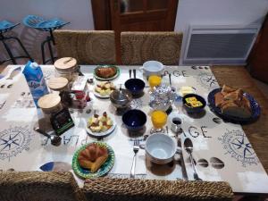 una mesa con comida para el desayuno y bebidas en ella en Gîtes Rose des Sables en Surtainville