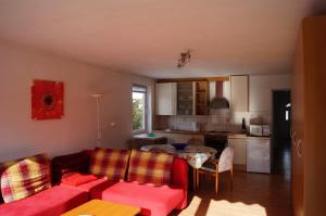 ein Wohnzimmer mit einem roten Sofa und einer Küche in der Unterkunft Apartments Krassnig in Krumpendorf am Wörthersee