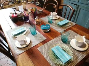 een houten tafel met borden, kopjes en servetten bij La Forge in Arcis-le-Ponsart