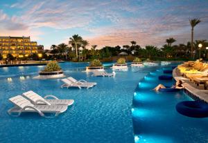 ein Resortpool mit Stühlen und ein Hotel im Hintergrund in der Unterkunft Steigenberger Aldau Beach Hotel in Hurghada