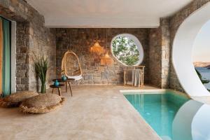 a bathroom with a swimming pool and a room with brick walls at Panormos Village Hotel in Mykonos