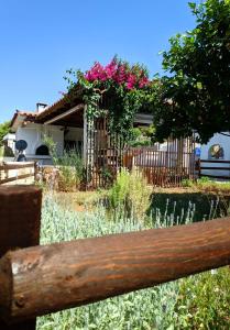 a wooden bench in a garden with pink flowers at Koel Country House in Áno Almirí