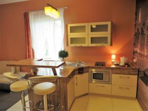a small kitchen with a sink and a counter with stools at City Apartments Protos in Knurów