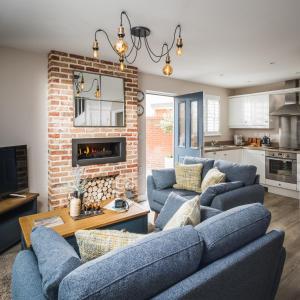 a living room with two blue couches and a brick wall at Owlers Cottage in Camber