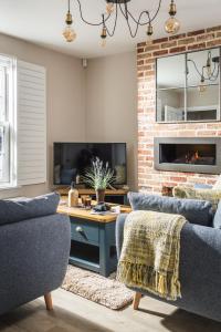 a living room with two couches and a fireplace at Owlers Cottage in Camber