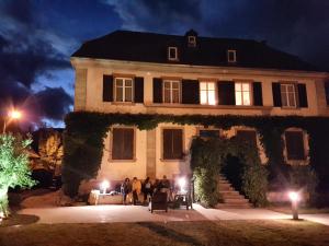 um grupo de pessoas em pé na frente de uma casa à noite em Ancien Presbytère Albert Schweitzer em Gunsbach