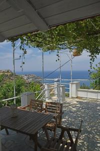 einen Holztisch und Stühle auf einem Balkon mit Meerblick in der Unterkunft MARE VISTA in Évdilos