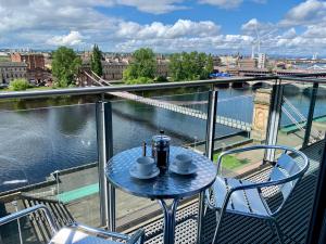 a table and chairs on a balcony with a view of a river at Principal Apartments - Clyde Waterfront Apartments in Glasgow