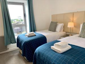 - une chambre avec 2 lits et des serviettes dans l'établissement Principal Apartments - Clyde Waterfront Apartments, à Glasgow