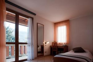 sypialnia z łóżkiem, biurkiem i oknem w obiekcie Hotel Oasi Verde w mieście Bienno