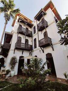 a white building with balconies and a palm tree at Kholle House in Zanzibar City