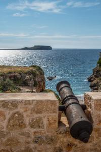 Un cannone su un muro di pietra vicino all'oceano di IPPOLA BOUTIQUE HOTEL a Érimos