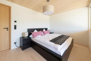 um quarto com uma cama preta e branca com almofadas cor-de-rosa em Zu Gast bei den Hagspiels em Hittisau