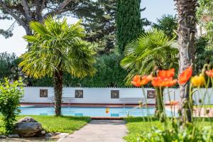 einen Pool in einem Garten mit Palmen in der Unterkunft Glanzhof Hotel & Apartments in Marling