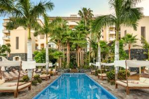 a hotel pool with lounge chairs and palm trees at Vincci Selección La Plantación del Sur in Adeje