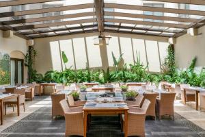 un restaurante con mesas, sillas y plantas en Vincci Selección La Plantación del Sur, en Adeje