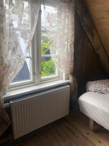a bedroom with a window with curtains and a radiator at A pearl in the center of the center of Thorhavn in Tórshavn