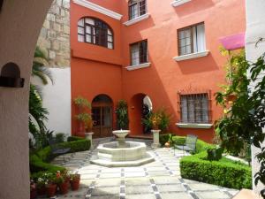 an orange building with a fountain in the courtyard at Hotel Trébol in Oaxaca City