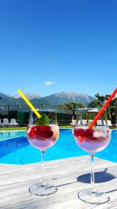 two wine glasses sitting on a table next to a pool at Sport Manca Garni Hotel in Radovljica