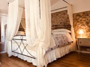 1 dormitorio con cama con dosel y cortinas blancas en GardaBeds Adults Only, en Castelnuovo del Garda