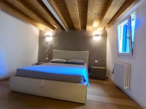 a bedroom with a bed with blue sheets and a window at Casa Calle Pescheria in Grado