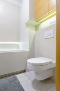 a white bathroom with a toilet and a sink at Dąbrowskiego Apartment in Poznań