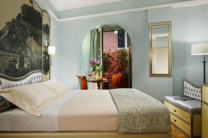 a bedroom with a bed and a chair and a mirror at Grand Hotel Savoia in Genoa