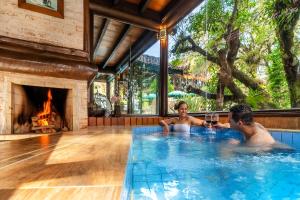 two people in a swimming pool with a fireplace at Pousada Cantos e Contos in Monte Verde