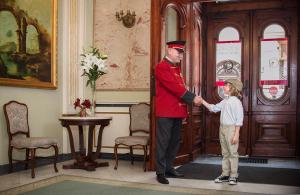 Ein Mann in Uniform schüttelt die Hand eines kleinen Mädchens in der Unterkunft Grand Hotel in Krakau