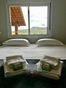 a bed with towels on it with a window at Vila dos Cristais in Alto Paraíso de Goiás