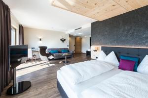 a bedroom with a white bed and a living room at Hotel Zum Tiroler Adler in Tirolo