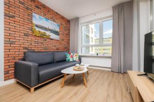 - un salon avec un canapé et un mur en briques dans l'établissement Stare Bielany 2-Bedroom Apartment, à Varsovie