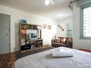um quarto com uma cama e uma sala de estar em Mariano - JK pertinho de tudo! em Porto Alegre