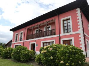 ein rosa und weißes Gebäude mit einem Balkon in der Unterkunft Hotel Puerta Del Oriente in Tresgrandas