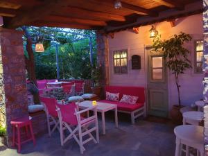 a patio with pink chairs and a table and chairs at Maniatis Garden in Achladies