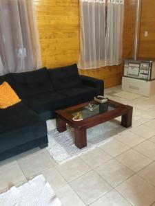 uma sala de estar com um sofá preto e uma mesa de centro em Casa de férias flor das acácias em Urubici