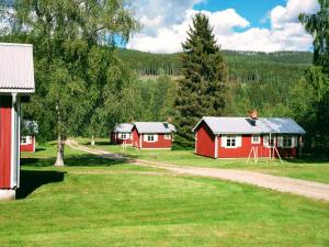 a group of red buildings in a field with trees at Klarälvsbyn in Sysslebäck