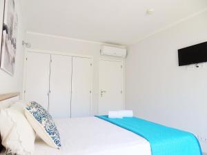 a white bedroom with a bed and a flat screen tv at Luz Apartments in Portimão