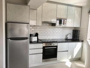 a kitchen with a stainless steel refrigerator and white cabinets at Luz Apartments in Portimão