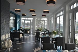 ein Esszimmer mit Tischen, Stühlen und Fenstern in der Unterkunft Hotel Garni Nordseejuwel in Horumersiel
