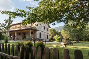 una vieja casa de piedra detrás de una valla de madera en Agriturismo Il Giardino Dei Ciliegi en Passaggio Di Assisi