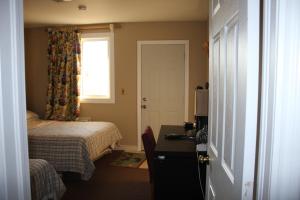 a bedroom with a bed and a desk and a window at Kent Motel in Chatham