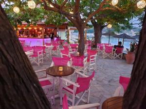 a group of chairs and tables with pink chairs at Maniatis Garden in Achladies