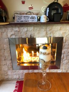 a wine glass with a dessert in front of a fireplace at 8 on Acacia Guesthouse in Bedfordview
