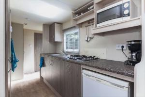 a small kitchen with a counter top and a microwave at BH Dommeldal Mobile home in Valkenswaard