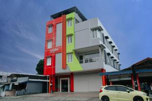 Un bâtiment coloré avec une voiture garée devant. dans l'établissement Super OYO 1006 Azzahra Guest House Syariah, à Ambon