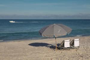 three chairs and an umbrella on the beach at Zota Beach Resort in Longboat Key